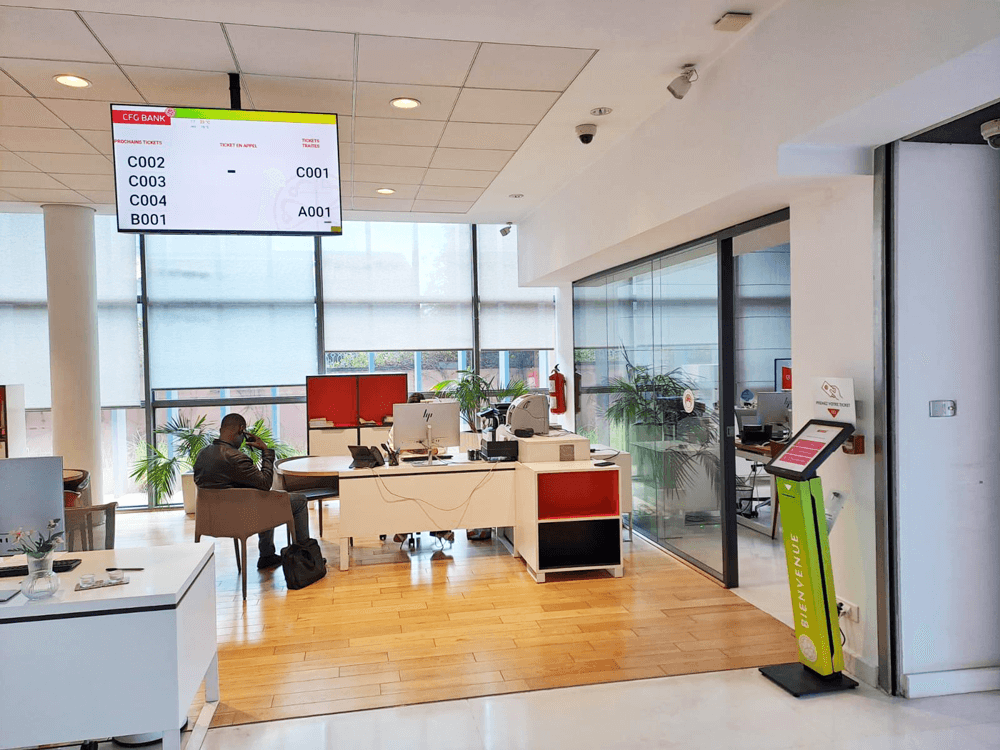 Staff assisting clients at service counters while Moviik’s queue management system displays active tickets. Staff assisting clients at service counters while Moviik’s queue management system displays active tickets.